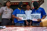 Pasuruan (Antara Pasuruan) - Kapolres Pasuruan AKBP Ricky Purnama (kiri) menunjukan barang bukti uang palsu (upal) dan tersangka pengedar upal, di ruang pidana umum (pidum) Polres Pasuruan, Bangil, Pasuruan, Jatim, Senin (8/9). Dari penangkapan dua tersangka tersebut Poores Pasuruan menyita upal sebanyak 200 lembar pecahan uang serataus ribu senilai Rp20 Juta, dua handphone, dari penagkapan tersebut tersangka dapat dikenakan hukuman Pasal 245  KUHP, tentang memiliki mengedarkan dan menyimpan uang palsu dengan ancaman hukman 15 tahun penjara. FOTO Adhitya Hendra/14/Chan.