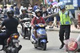 Seorang polisi menghentikan pelajar bersepeda motor saat penertiban pelajar pelanggar lalu lintas di Denpasar, Bali, Senin (8/9). Penertiban tersebut digelar akibat maraknya pelanggaran lalu lintas oleh pelajar terutama yang masih di bawah umur 17 tahun, sekaligus untuk menekan angka kecelakaan lalu lintas yang mencapai 2 ribu kasus per tahun di Bali. ANTARA FOTO/Nyoman Budhiana/nym/2014.