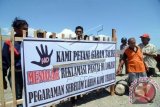 Sejumlah petani garam memasang spanduk di pagar blokade jalan masuk penimbunan pantai (reklamasi) di pantai Talise Palu, Sulawesi Tengah, Jumat (19/9). Petani garam memblokade kawasan yang terletak dekat penggaraman mereka itu karena hingga saat ini pemerintah setempat belum membayar lahan garam mereka yang dipastikan akan terimbas dengan adanya reklamasi tersebut. ANTARA FOTO/Basri Marzuki/nym/2014