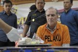 Petugas Bea Cukai dan kepolisian memperlihatkan hasil uji terhadap barang bukti kapsul kokain di hadapan pelaku penyelundupan yang merupakan warga negara Jerman, Naumann Hans Peter (kedua kanan) saat pengungkapan kasus penyelundupan narkoba di Bea Cukai Bandara Ngurah Rai, Denpasar, Sabtu (27/9). Warga negara Jerman tersebut ditangkap setibanya di Bandara Ngurah Rai karena berupaya menyelundupkan 239 gram kokain dalam kemasan 17 kapsul dengan cara ditelan. ANTARA FOTO/Nyoman Budhiana/Koz/pd/14.