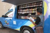 Kediri (Antara Jatim) - Seorang pengunjung membaca koleksi buku di mobil pintar yang ada di kawasan Simpang Lima Gumul (SLG) Kabupaten Kediri, Jawa Timur, Minggu (19/10). Mobil pintar itu sengaja berada di kawasan SLG, agar pengunjung juga bisa membaca, demi menambah wawasan. FOTO Asmaul Chusna 