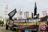 Mahasiswa muslim dari perguruan tinggi Aceh mengusung bendera dan spanduk saat aksi di simpang Lamprit, Banda Aceh, Jumat (17/10).  Mereka menuntut peran khilafah (pemimpin) tegak di Indonesia untuk mengutamakan kesejahteraan, pendidikan murah, kesehatan gratis dan menumpas korupsi yang menguras uang rakyat berdampak pada kemiskinan.ANTARAACEH.COM/Ampelsa/14