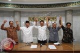 Pengurus Pura Agung Wira Satya Buana Wayan Wiradmaja (kiri), Ketua GP Ansor Nusron Wahid (kedua kiri), Koordinator Doa dan Zikir Nasional Zuhairi Misrawi (tengah), Ketua Pusat Informasi KWI Romo Beny Susetyo, dan Pengurus Dewan Masjid Indonesia Herry Sucipto, mengangkat tangan sebagai simbol persatuan lintas agama di Masjid Sunda Kelapa, Jakarta, Jumat (17/10). Masyarakat lintas agama akan menggelar doa bersama pada Minggu (19/10) guna menyambut pelantikan Jokowi-JK sebagai Presiden dan Wakil Presiden 2014-2019. ANTARA FOTO/Akbar Nugroho Gumay/wdy/14