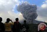 Warga menyaksikan Gunung Sinabung yang kembali meletus di Desa Tiga Pancur, Simpang Empat, Karo, Sumut, Senin (13/10). Letusan yang mengeluarkan material vulkanik disertai suara gemuruh. ANTARA FOTO/Septianda Perdana