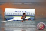 Sejumlah penumpang menolong rekannya untuk keluar dari pesawat saat simulasi kecelakaan pesawat Jalak Airlines di dekat Bandara Ngurah Rai, Pantai Tuban, Badung, Selasa (18/11). Latihan tanggap darurat tersebut melibatkan 742 personel dari berbagai unsur untuk meningkatkan kesigapan para petugas dalam menanggulangi keadaan darurat di bandara internasional itu. ANTARA FOTO/Nyoman Budhiana/i018/2014.