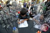 Anak-anak mengikuti 'coaching clinic' membuat wayang dari limbah plastik dalam acara Pentas Seni Budaya dan Edutainment Sanggar Anak di Taman Ismail Marzuki, Jakarta, Minggu (23/11). Kegiatan itu merupakan rangkaian peringatan Hari Anak Sedunia terdiri dari empat kegiatan utama, yakni pertunjukan Sanggar Anak, Coaching Clinic, dan Pameran Bandar Enjoy Jakarta, serta lomba-lomba kesenian anak. ANTARA FOTO/Fanny Octavianus/ama/14.