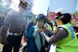 Polisi wanita memasang helm ke pengendara motor yang terjaring razia tidak memakai helm saat Operasi Zebra Lodaya 2014 di Jalan Raya Tegar Beriman, Cibinong, Bogor, Jabar, Senin (8/12). Operasi yang bekerja sama dengan CSR perusahaan dengan membagikan helm gratis tersebut dilakukan sebagai upaya sosialisasi kepada masyarakat untuk tertib berlalu lintas dan menegakkan aturan di masyarakat. (Foto Antara/Jafkhairi)