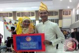 Pasangan Nanang dan Galuh Banjar anggota Perkumpulan Mahasiswa Kalimantan Selatan (PMKS) Malang menunjukan penghargaan pemenang Stand Terpavorit di ajang Festival Kampung Budaya 2014 di Universitas Brawijaya, Malang, Jumat (19/12). Stand PMKS membawa konsep Pasar Terapung menampilkan jukung, hiasan air guci, kain sasirangan, dan kuliner khas Kalimantan Selatan.(Foto Antaranews Kalsel/Asmuni/pmks/e)