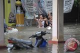 Sejumlah warga berfoto di genangan air saat terjadi banjir di kawasan Perumahan Padang Asri, Denpasar, Jumat (20/2). Hujan deras yang mengguyur wilayah Bali selatan menyebabkan sejumlah kawasan di Denpasar tergenang dan 2 orang dilaporkan hilang akibat terseret arus air. ANTARA FOTO/Nyoman Budhiana/i018/2015.