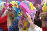 Surabaya (Antara Jatim) - Sejumlah perempuan keturunan Tionghoa menyelesaikan pemakaian hijab berbagai kreasi di Masjid ChengHo, Surabaya, Jawa Timur, Kamis (19/2). Komunitas Wirausaha Muslim meluncurkan program 1000 hijab untuk mualaf keturunan Tionghoa yang bertujuan untuk menyiarkan ajaran agama islam dengan cara berbeda yang bertepatan dengan perayaan Tahun Baru Imlek 2566 untuk saling bersilaturahmi. FOTO M Risyal Hidayat/EI/15