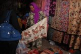 Pamekasan (Antara Jatim) - Pedagang menawarkan kain kepada pembeli di Sentra Pasar Batik 17 Agustus, Pamekasan, Madura, Jatim, Minggu (8/3). Sentra batik yang hanya buka pada hari Kamis dan Minggu tersebut menjual berbagai jenis motif batik khas Madura yang dijual dengan harga Rp 25ribu sampai Rp 250ribu tergantu bahan serta motif. Foto/Adhitya Hendra/15.