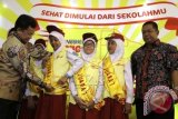 Dirjen Pendidikan Dasar Kementerian Pendidikan dan Kebudayaan Hamid Muhamamad menyematkan tanda juara pertama kepada siswi SDN 3 Sedayu Yogyakarta saat menghadiri acara pemberian Juara Nasional Dokter Kecil Mahir Gizi 2014 di SDN Gongdangdia 01, Menteng, Jakarta, Jumat, (20/3).Dokter Kecil Mahir Gizi merupakan program Caravan Gizi Nestle Dancow bekerjasama dengan perhimpunan Dokter Gizi Medik Indonesia dan Kemendikbud bertujuan untuk mendorong para siswa-siswi Sekolah menjadi agen perubahan di sekolah mereka khususnya di bidang nutrisi, kesehatan dan kebersihan diri mendukung pencapaian target Millenium Development Goals (MDGs) tahun 2015 yakni penurunan angka gizi buruk sampai 15,5 persen. ANTARA FOTO/Teresia May/wdy/15.