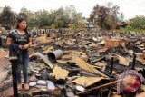 Seorang jurnalis menyisir lokasi kebakaran di Desa Sepaso Kecamatan Bengalon Kabupaten Kutai Timur Kalimantan Timur, Minggu (22/3). Peristiwa kebakaran yang terjadi pada Jumat (20/3) malam pukul 21.00 Wita itu menghanguskan delapan rumah pribadi dan 46 rumah barak, mengakibatkan 146 jiwa harus mengungsi dengan kerugian ditaksir lebih dari Rp1 miliar. (Adi Sagaria/ANTARA Kaltim)