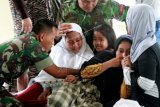 Rekan Serda Hendri menghibur anak almarhum saat jenazah tiba dari kawasan Batee Pila Desa Alue Papeun Aceh utara, Provinsi Aceh. Selasa (24/3). Dua Intel Kodim 0103 Aceh Utara Serda Hendri dan Sertu Indra diculik sekelompok pria bersenjata pada Senin (23/3) dan ditemukan tewas dengan hampir seluruh bahagian tubuh korban alami luka tembak. Polisi menemukan 12 selongsonag AK-47 dan 13 butir seloangsong M-16. ANTARA FOTO/Rahmad/ed/pd/15