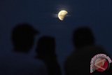 Tiga pengunjung menyaksikan gerhana bulan yang terlihat dari Pantai Lebih, Gianyar, Bali, Sabtu (4/4). Gerhana yang berlangsung 3 jam 29 menit tersebut mulai sekitar pukul 18.25 Wita yaitu saat bulan baru terbit sehingga gerhana  bisa disaksikan dari Indonesia bagian timur dari fase awal hingga akhir gerhana. ANTARA FOTO/Nyoman Budhiana/i018/2015.