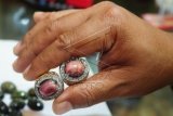 Penjual Cinderamata khas Kalbar memperlihatkan cincin berikat batu Red Borneo di Pontianak, Jumat (10/4). Cincin batu Red Borneo yang memiliki ciri khas merah muda polos atau terdapat guratan berwarna hitam tersebut, didatangkan dari Banjarmasin serta dijual seharga Rp250 ribu hingga jutaan rupiah per buah sesuai warna dan ukurannya. ANTARA FOTO/Jessica Helena Wuysang/ed/pd/15