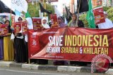 Aktivis Hizbut Tahrir Indonesia (HTI) Aceh membawa poster dan bendera saat aksi di bundaran Simpang Lima, Banda Aceh, Kamis (16/4). Aktivis HTI mengingat pemerintah Indonesia saat ini terancam neoliberalisme dan neoimperalisme yang menyusup ke sektor  publik seperti migas, listrik dan transportasi  sehingga perlu diselamatkan dengan syariah dan khuilafah. ANTARAACEH.COM/Ampelsa/15