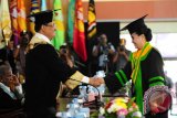 Rektor Universitas Tanjungpura, Thamrin Usman (kiri) menyalami Joyce Linda Wuysang (kanan), wisudawan dari Program Studi Magister Manajemen Agribisnis Fakultas Pertanian yang meraih predikat wisudawan tercepat dengan Indeks Prestasi Kumulatif (IPK) tertinggi 4.00, saat upacara wisuda Program Sarjana dan Magister Universitas Tanjungpura , di Rektorat Untan, Pontianak, Kamis (30/4). Untuk periode III tahun akademik 2014/2015, Universitas Tanjungpura meluluskan 1.057 wisudawan yang terdiri dari 7 wisudawan program Diploma (D3), 933 wisudawan program Sarjana dan 117 wisudawan Magister. ANTARA FOTO/Jessica Helena Wuysang/15