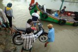 Pamekasan (Antara Jatim) - Buruh menaikkan sepeda motor ke atas perahu tambangan, di Pelabuhan Desa Pegagan, Pademawu, Pamekasan, Jatim, Jumat (1/5). Pemerintah berencana  menaikkan upah minumum tiap lima tahun sekali. Foto/Saiful Bahri/15/Uki