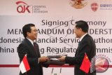 Ketua Dewan Komisioner Otoritas Jasa Keuangan (OJK) Muliaman Dharmansyah Hadad (kiri) bertukar dokumen dengan Wakil Ketua China Banking Regulatory Commission (CBRC) Zhou Mubing (kanan) usai di tandatangani di Jakarta, Kamis (4/6). Dalam nota kesepahaman tersebut OJK dan CBRC bekerjasama dalam mencangkup kegiatan pertukaran informasi dan peningkatan kapasitas pengawasan kedua otoritas yang diharapkan dapat mendukung perluasan kegiatan usaha industri perbankan Indonesia di China. ANTARA FOTO/Muhammad Adimaja/wdy/15.