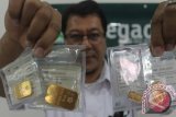 Petugas menunjukkan empat keping emas 24 karat dengan bobot masing-masing 5 gram, 10 gram, 25 gram dan 50 gram di Kantor Pegadaian Cabang Tulungagung, Jawa Timur, Senin (8/6). Lini bisnis ivestasi emas yang kembali diluncurkan PT Pegadaian setempat sejak 2010 dengan sistem pembayaran tunai maupun kredit tersebut mengalami kenaikan sekitar 20 persen dengan omzet rata-rata mencapai 300-400 gram/bulan atau sekitar Rp250 juta/bulan. ANTARA FOTO/Destyan Sujarwoko/Zk/15ah tangga TKI sukses. ANTARA FOTO/Destyan Sujarwoko/Zk/15