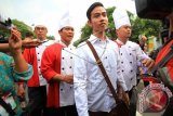 Putra sulung Presiden Joko Widodo, Gibran Rakabuming Raka (dua kanan) bersama sejumlah juru masak berjalan menuju Media Center Jokowi Mantu sebelum memberikan keterangan pers di Sumber, Solo, Jawa Tengah, Selasa (9/6). Dalam kesempatan itu, Gibran memberikan keterangan pers mengenai makanan dan katering yang akan disuguhkan kepada tamu dalam pelaksanaan prosesi pernikahannya pada Kamis (11/6). ANTARA FOTO/Maulana Surya/wdy/15.