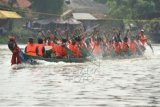 Sejumlah pria mendayung perahu naga pada lomba balap perahu naga dalam rangkaian perayaan Peh Cun di sungai Cisadane, Tangerang, Banten, Minggu (21/6). Tradisi lomba perahu naga merupakan salah satu dari berbagai tradisi dalam perayaan peh cun di Sungai Cisadane. ANTARA FOTO/Paramayuda/pd/15