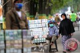 Seorang pejalan kaki melintasi di depan warga yang menawarkan jasa penukaran uang di tepi jalan Lambung Mangkurat Banjarmasin, Rabu (24/6). Jasa penukaran uang jalanan untuk keperluan Ramadan dan Idul Fitri sudah marak di Banjarmasin dengan nilai keuntungan 5-10 persen di setiap transaksi. Foto Antaranews Kalsel/Herry Murdy Hermawan