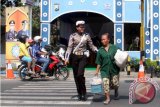 Petugas membantu seorang pejalan kaki menyeberangi jalan yang mulai ramai oleh pemudik di jalur selatan Trenggalek, Jawa Timur, Senin (13/7). Meningkatnya intensitas kendaraan pemudik di jalur alternatif tersebut membuat kerawanan kecalakaan lalu lintas ikut meningkat. Antara Jatim/Foto/Destyan Sujarwoko/15