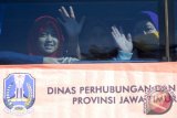 Sejumlah pemudik melambaikan tangan didalam bus ketika mudik bareng gratis 2015 di Surabaya, Jawa Timur, Selasa (14/7). Mudik gratis yang diselenggarakan oleh pemerintah provinsi Jawa Timur tersebut menyediakan sekitar 685 bus yang diikuti oleh 68.385 orang pemudik dengan tujuan sejumlah daerah di Jawa Timur. Antara Jatim/M Risyal Hidayat/15