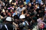 Petugas keamanan mengevakuasi seorang anak yang terhimpit saat antre menghadiri open house di kediaman Wakil Presiden Jusuf Kalla di Makassar, Sulawesi Selatan, Minggu (19/7). Open house tersebut dihadiri ratusan masyarakat Kota Makassar dan sekitarnya. ANTARA FOTO/Abriawan Abhe/wdy/15.