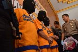 Kapolres Madiun AKBP Yoyon Tony Surya Putra (kanan) menginterogasi tersangka (berpenutup wajah) saat merilis pengungkapan kasus pembobolan toko emas di Mapolres Madiun, Jawa Timur, Senin (27/7). Polres Madiun menangkap tiga dari empat orang tersangka (seorang masih buron) kasus pembobolan dan pencurian sekitar 1,5 kg emas di toko Artama di Mejayan, Kabupaten Madiun 4 Juli 2015 lalu, dengan menggunakan peralatan las dan gerinda untuk membobol pintu dan brankas. Antara Jatim/Foto/Siswowidodo/15

