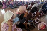 Warga memperlihatkan Kartu Elektronik PKH saat pencairan dana bantuan Program Keluarga Harapan (PKH) di kantor Kecamatan Bangil, Pasuruan, Jawa Timur, Minggu (23/8). Masyarakat yang terdata dalam penerima PKH tersebut selain mendapatkan dana bantuan pokok sebesar Rp500.000 per tahun juga mendapat dana bantuan lain hingga Rp4.200.000 per tahun tergantung kriteria dan jumlah anak dalam keluarga. Antara Jatim/Moch Asim/Zk/15