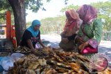 Seorang warga menjual ikan asap di sekitar Pantai Kenjeran Surabaya, Jawa Timur, Jumat (28/8). Menurut pedagang ikan setempat, naiknya harga daging sapi menjadi peluang meningkatnya penjualan mereka karena sebagian masyarakat beralih ke daging ikan dengan harga yang tetap stabil. Antara Jatim/Fandhy Rizal/SHP/15
