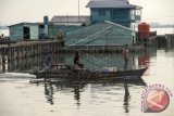 Tiga orang nelayan menaiki kapal motor pong-pong melintas di antara rumah penduduk di Pulau Sedanau, Kabupaten Natuna, Kepulauan Riau, Jumat (4/9). Sedanau merupakan salah satu kelurahan di kecamatan Bunguran Barat yang kotanya berdiri di atas air laut. ANTARA FOTO/Widodo S. Jusuf/wdy/15.
