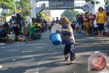 Seekor kera dalam kondisi terikat tali membawa ember dan payung kecil saat diajak mengamen pemiliknya di areal hari tanpa kendaraan bermotor (Car Free Day) di Kota Madiun, Jawa Timur, Minggu (6/9). Meski ditentang para pencinta binatang, ekspolitasi kera untuk mencari uang bagi pemiliknya yang dikemas dalam bentuk hiburan topeng monyet masih terus terjadi. Antara Jatim/Foto/Siswowidodo/ZK/15.



