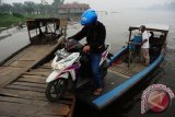 Pengendara mendorong motornya menaiki dermaga dari kapal motor di dermaga Tebang Kacang, Kecamatan Rasau Jaya, Kabupaten Kubu Raya, Kalbar, Senin (28/9). Kapal motor yang terbuat dari kayu tersebut, dapat mengantarkan warga yang ingin menyeberang ke sejumlah desa di Kecamatan Rasau Jaya dengan biaya  Rp2 ribu per orang atau Rp5 ribu per kendaraan. ANTARA FOTO/Jessica Helena Wuysang/15