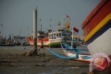 Warga melintas di sekitar puluhan perahu yang ditambatkan di pelabuhan Branta Pesisir, Pamekasan, Jatim, Senin (5/10). Dalam dua pekan terakhir sebagian  nelayan di Madura tidak melaut karena angin dan ombak besar. Antara Jatim/Saiful Bahri/zk15
