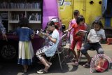 Sejumlah anak membaca buku yang disediakan gratis di mobil perpustakaan keliling, Tanah Abang, Jakarta Pusat, Minggu (11/10). Perpustakaan keliling yang disediakan oleh Kantor Perpustakaan dan Arsip Jakarta Pusat tersebut bertujuan untuk menciptakan serta meningkatkan budaya membaca bagi anak usia dini. ANTARA FOTO/Sigid Kurniawan/wdy/15.