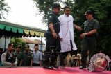 Terpidana kasus sabung ayam dikawal petugas kepolisian dan polisi Syariat Islam dikawal petugas saat akan menjalani hukum cambuk di halaman Masjid Tgk Dianjung, Desa Peulanggahan, Kutaraja, Banda Aceh, Aceh, Jumat (6/11). Sesuai putusan Mahkamah Syariah Banda Aceh tiga orang terpidana kasus sabung ayam dihukum tiga hingga empat kali cambuk setelah dikurangi masa tahanan kerena melanggar peraturan daerah (qanun) nomor 13/2003 tentang perjudian. ANTARA FOTO/Irwansyah Putra/nz/15.