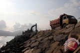 Pekerja mengoperasionalkan alat berat untuk mempercepat pembangunan tanggul pemecah ombak (break water) di Pelabuhan Popoh, Tulungagung, Jawa Timur, Jumat (13/11). Tanggul pemecah ombak sepanjang 100 meter di Pelabuhan Popoh dibangun pemerintah secara bertahap menggunakan dana APBN dengan tujuan melindungi kapal-kapal nelayan yang lego jangkar di kolam labuh dari terjangan ombak atau dampak gelombang air pasang. Antara Jatim/Foo/Destyan Sujarwoko/15