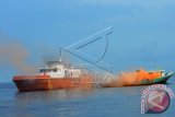 Kapal pemadam Badan SAR Nasional (Basarnas) kota Gorontalo memadamkan kapal bermuatan BBM ilegal yang terbakar pada simulasi gabungan Basarnas di Teluk Tomini, Parigi, Sulawesi Tengah, Rabu (2/12). Simulasi gabungan yang melibatkan unsur, TNI, Polisi, PMI, Kementerian kesehatan, dan KPLP itu untuk melatih kesigapan menangani situasi bencana sesuai prosedur yang terkordinasi. ANTARA FOTO/Fiqman Sunandar.