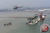 Sebuah Heli Bell 412EP milik Skuadron Udara 400 Wing Udara 1 Puspenerbal melintas di atas Dermaga Terminal Teluk Lamong Perairan Surabaya, Jawa Timur, Senin (7/12). Terminal Teluk Lamong merupakan terminal semi otomatis pertama di Indonesia, dan seluruh operasional memanfaatkan energi yang ramah lingkungan, seperti penggantian bahan bakar dari fosil ke gas, pemanfaatan energi matahari untuk penerangan, hingga pengopersian peralatan secara elektrik dengan kendali di ruang kontrol. Antara Jatim/M Risyal Hidayat/zk/15