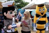 Warga menerima kartu Surat Izin Mengemudi (SIM) dari boneka berisi orang dengan kostum polisi pada peluncuran SIM Online di Alun-alun Serang, Banten, Minggu (6/12). Peluncuran Layanan SIM online di seluruh Polda dimaksudkan untuk memudahkan masyarakat memperpanjang masa berlaku SIM. ANTARA FOTO/Asep Fathulrahman/ama/15