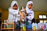 Dua Siswi memperagakan pengunaan alat penjernih minyak jelantah di ruang laboratorium SMA Negeri 2 Kudus, Jawa Tengah, Selasa (15/12). Alat penjernih minyak jelantah yang menggunakan bahan baku kulit pisang kepok yang di beri nama ECOFABELS (Waste Cooking Oil's Purification With Banana Peels) temuan siswa yang menjadi juara1 kategori High School dalam 'Insight Challenge ITB insight festival 2015 di Bandung tersebut dapat mengurangi kandungan asam lemak jenuh pada minyak jelantah lebih dari 50%. ANTARA FOTO/Yusuf Nugroho/wdy/15.