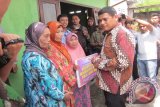 Wali Kota Kediri Abdullah Abu Bakar berbincang dengan warga penerima bantuan program perbaikan rumah di Kelurahan Burengan, Kecamatan Kota, Kediri, Jawa Timur, Kamis (17/12). Pemkot menganggarkan perbaikan rumah untuk 100 rumah warga pada 2015, dan akan dinaikkan menjadi 200 rumah pada 2016. Setiap rumah warga kurang mampu yang diperbaiki mendapatkan bantuan uang tunai Rp10 juta. Antara Jatim/Foto/Asmaul Chusna/15 