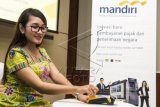 Seorang karyawan membayar pajak melalui mini ATM saat peluncuran sistem Modul Penerimaan Negara Generasi 2 (MPN G2) di Plaza Mandiri, Jakarta, Selasa (15/12). Bank Mandiri bersama Kementerian Keuangan mengembangkan sistem Modul Penerimaan Negara Generasi 2 (MPN G2) untuk memudahkan pembayaran setoran penerimaan negara, baik pajak maupun non pajak. Hingga Oktober 2015, realisasi transaksi penerimaan negara melalui Bank Mandiri mencapai 2,8 juta transaksi dengan nilai Rp263,12 triliun. ANTARA FOTO/M Agung Rajasa/kye/15.