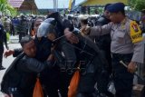 Seorang petugas kepolisian yang terluka dibawa rekannya ketika terjadi kericuhan dengan massa pendukung salah satu calon gubernur Kaltara di Kawasan Pemprov Kaltara, Bulungan, Sabtu (19/12). Aksi massa pendukung pasangan calon nomor satu Yusuf SK dan Martin Bila untuk menolak hasil pleno yang dilakukan oleh KPUD itu berakir ricuh dengan membakar sebuah mobil dan gedung serba guna Kantor Gubernur Kaltara. ANTARA FOTO/str-PRY