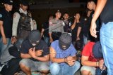 Petugas kepolisian menjaga sejumlah pelaku pengedar narkoba jenis sabu-sabu yang ditangkap di Sulawesi Selatan saat tiba di Pelabuhan Tunon Taka, Kabupaten Nunukan, Kalimantan Utara, Senin (28/12) malam. Sebanyak tujuh anggota komplotan pengedar sabu-sabu tersebut ditangkap atas hasil pengembangan penangkapan tersangka asal Malaysia dengan barang bukti 3,5 kg sabu-sabu pada pekan lalu. ANTARA FOTO/M Rusman