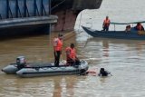 Dua petugas Ditpolair Polda Jambi memandu rekannya yang bersiap melakukan penyelaman untuk mencari korban kapal tenggelam di Sungai Batanghari, Kumpeh, Muarojambi, Jambi, Senin (4/1). Basarnas setempat menyebutkan, sebanyak 23 penumpang kapal tug boat yang merupakan pekerja salah satu perusahaan di daerah itu dilaporkan tenggelam dan tiga di antaranya dinyatakan hilang setelah kapal yang mereka tumpangi terbalik. ANTARA FOTO/Wahdi Septiawan/foc/16.